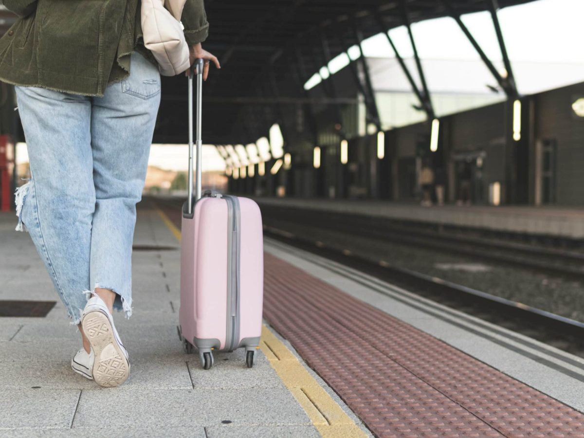 Frau mit Koffer am Bahnsteig