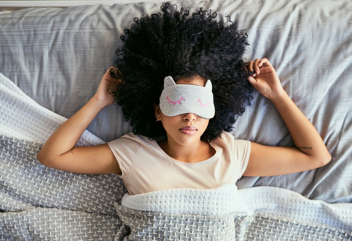 Shot of a young woman sleeping with a mask on in bed