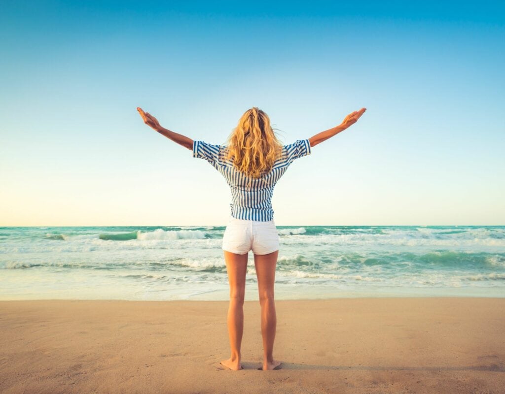 Femme sur la plage avec les bras en l'air