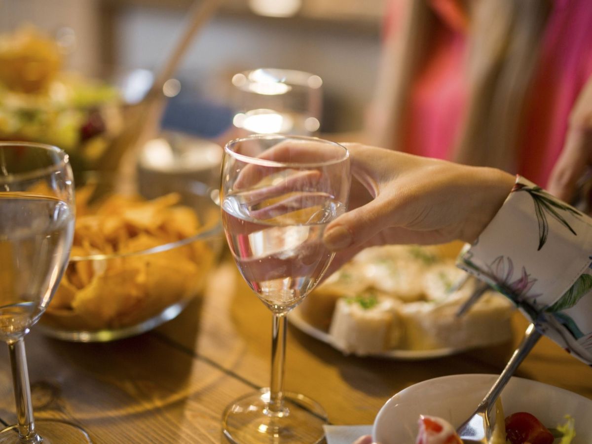 Hände mit Weinglas am gedeckten Tisch