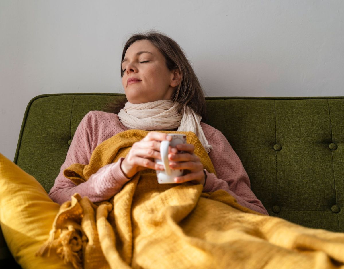 Frau krank auf dem Sofa mit Tee