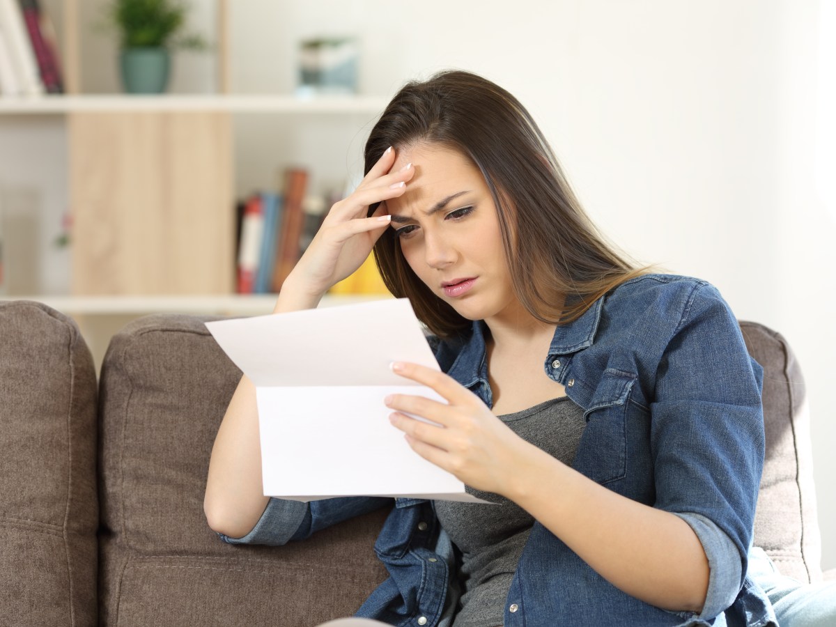 Frau hält Brief in der Hand und schaut verärgert.