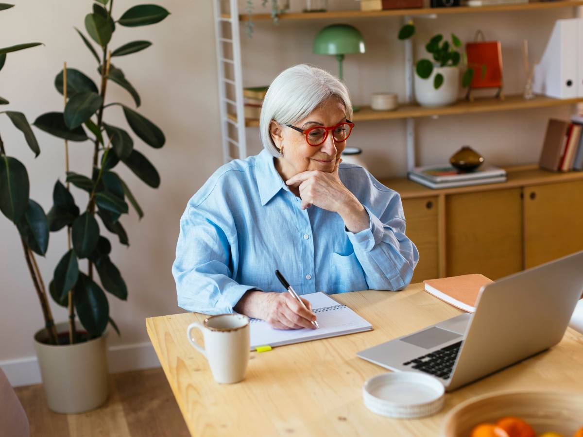 Ã„ltere Dame arbeitet vor dem Laptop.