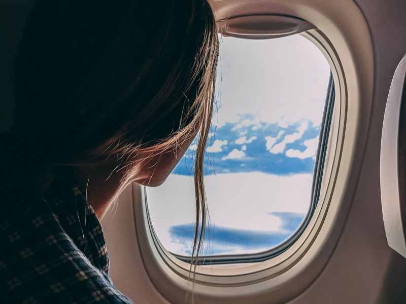 Frau blickt aus dem Fenster im Flugzeug