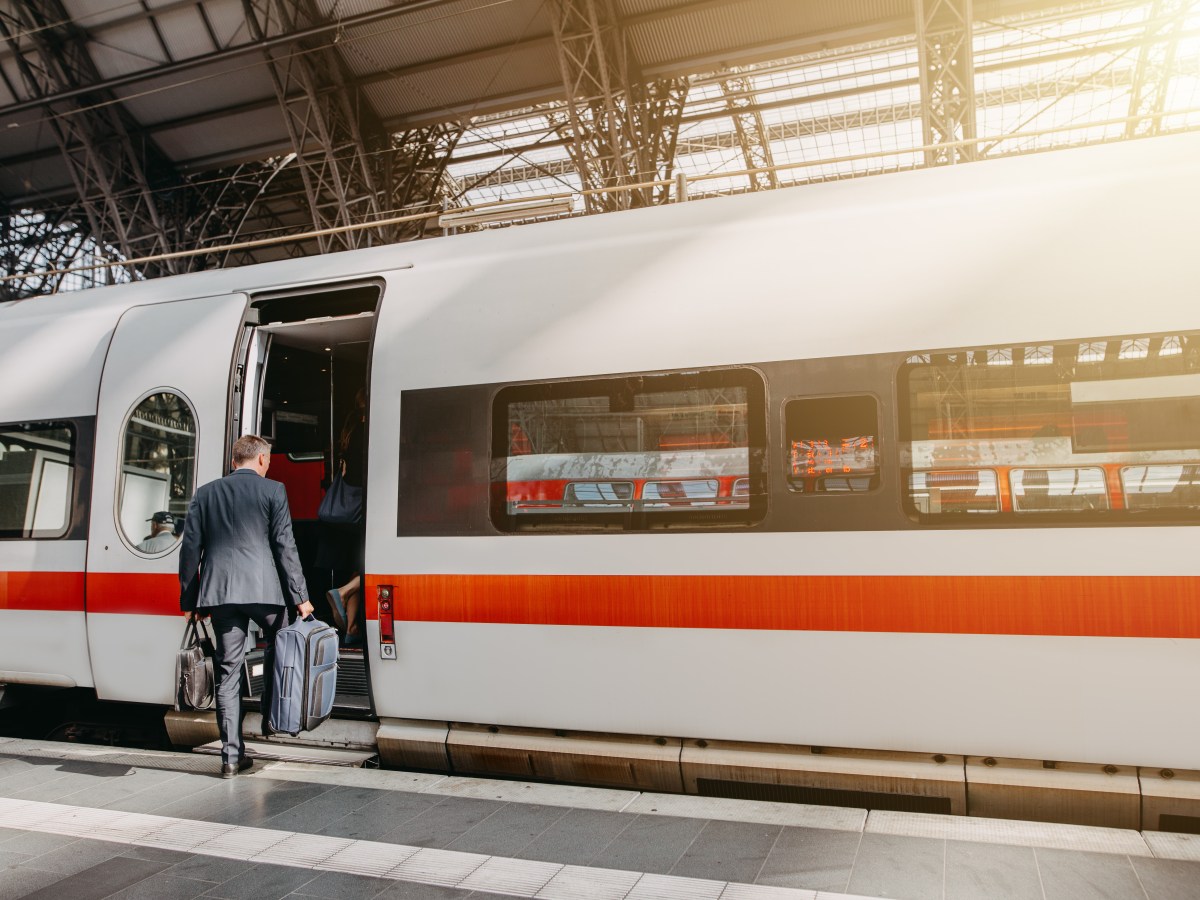 Ein Mann steigt mit zwei Koffern in einen ICE der Deutschen Bahn.