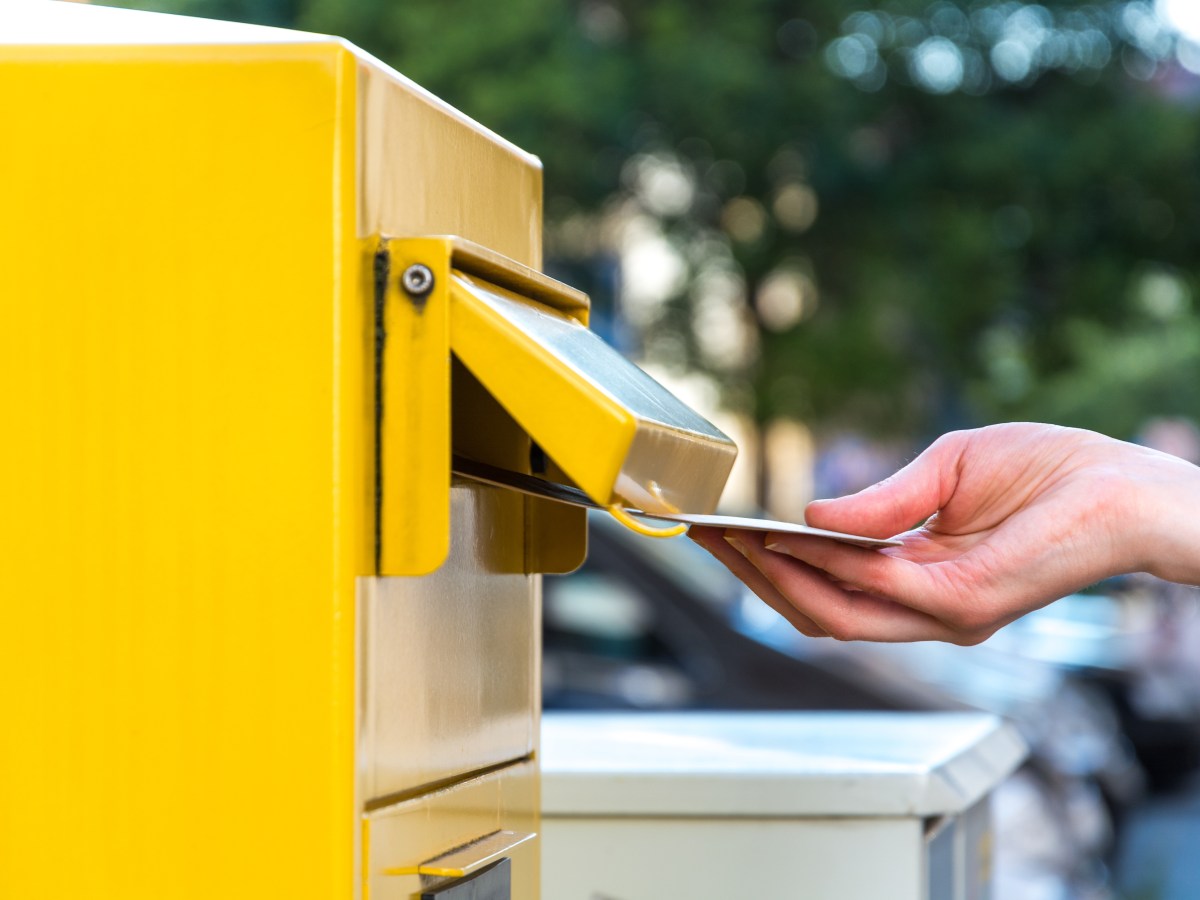 Person schmeiÃŸt einen Brief in einen Briefkasten der Deutschen Ost.