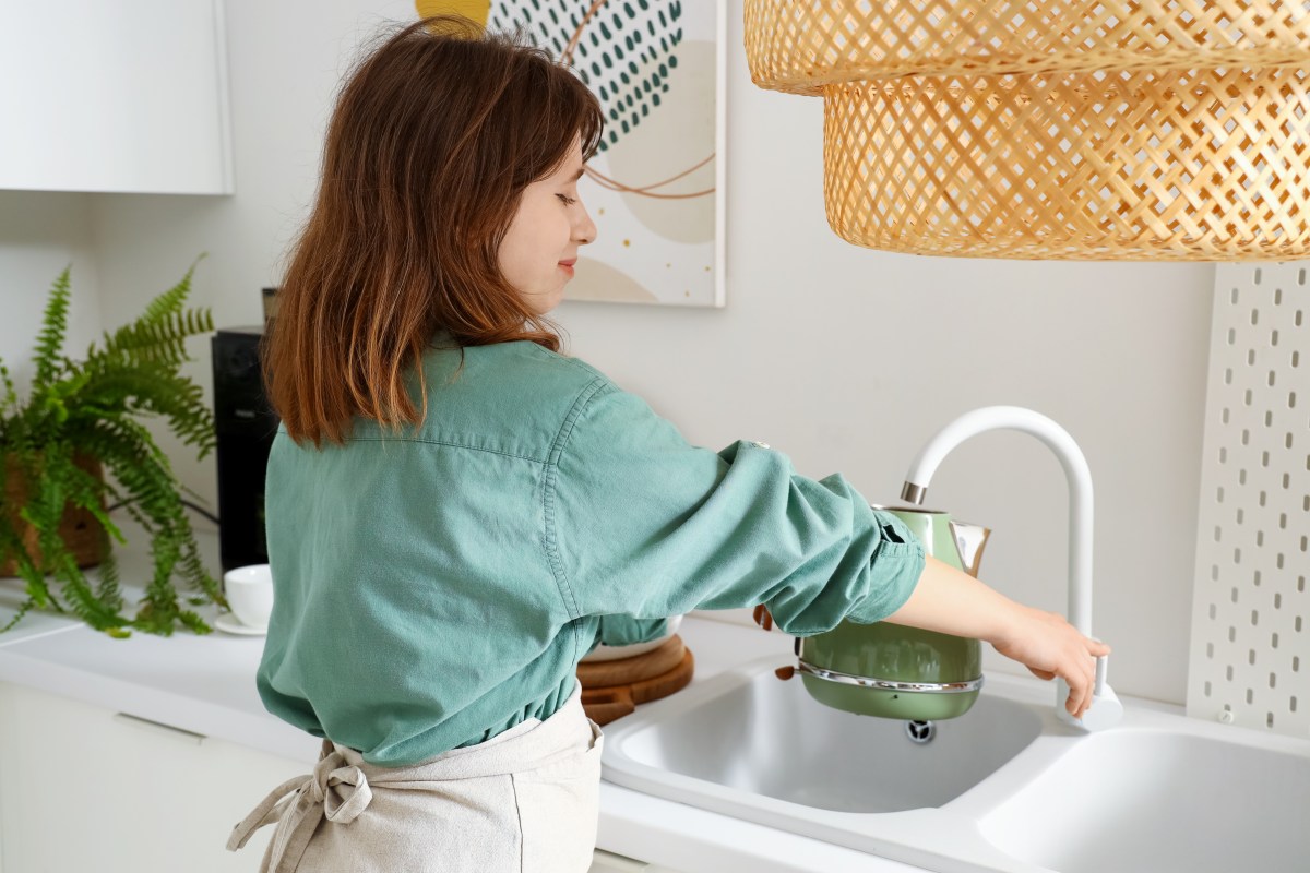 Frau befüllt Wasserkocher