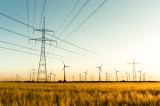 Strommasten im Kornfeld und WindrÃ¤der im Sonnenuntergang.