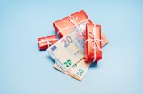 Draufsicht auf verpackte Weihnachtsgeschenke und Euro-Banknoten auf blauem Hintergrund