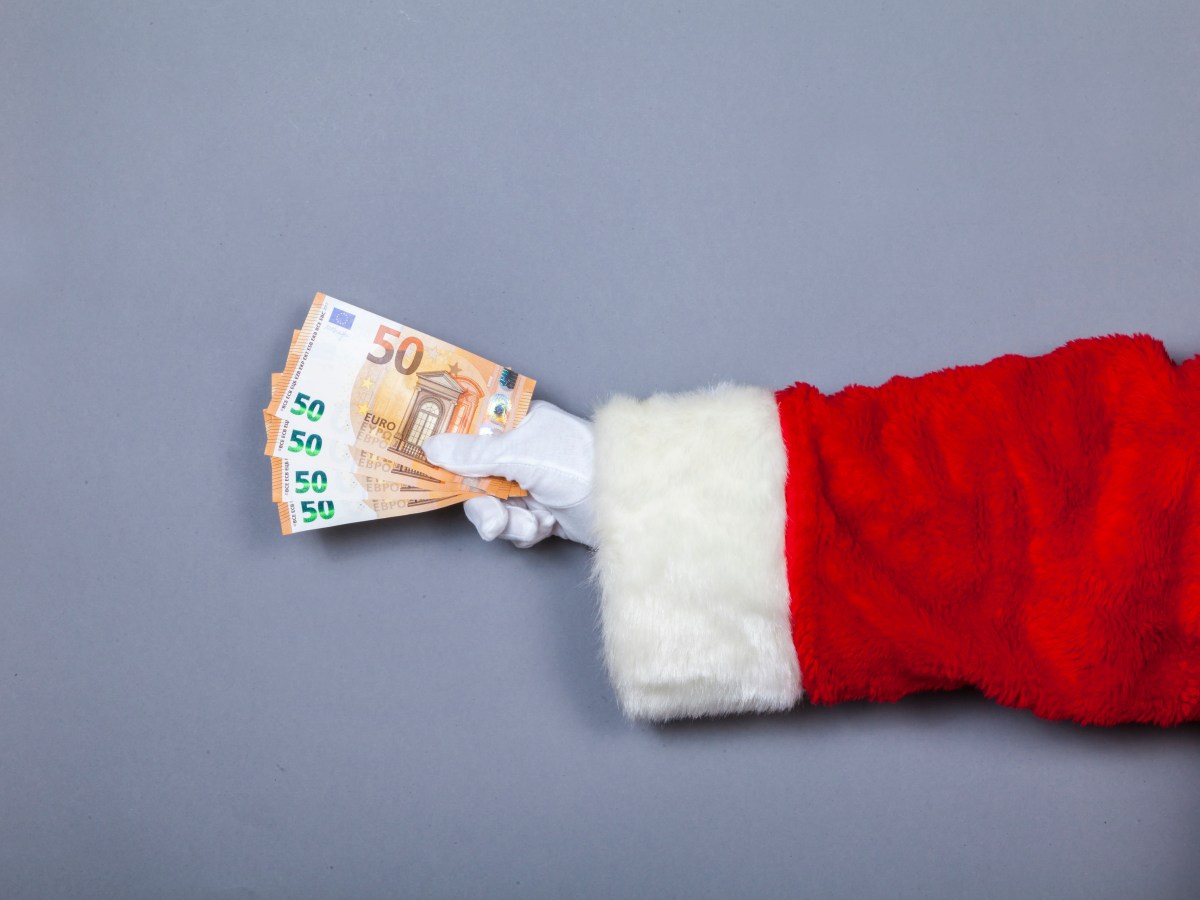 Weihnachtsmann hält 50-Euro-Scheine in Hand