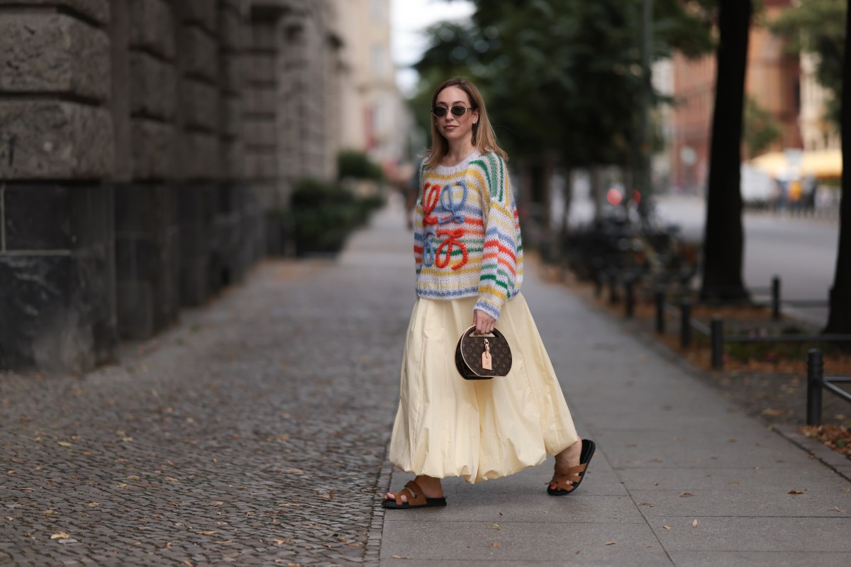 Frau mit Kleid und Pulli geht Ã¼ber StraÃŸe