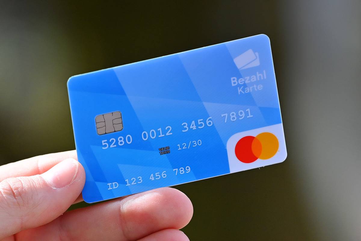 Eine Person hält eine blaue Bezahlkarte in der Hand.