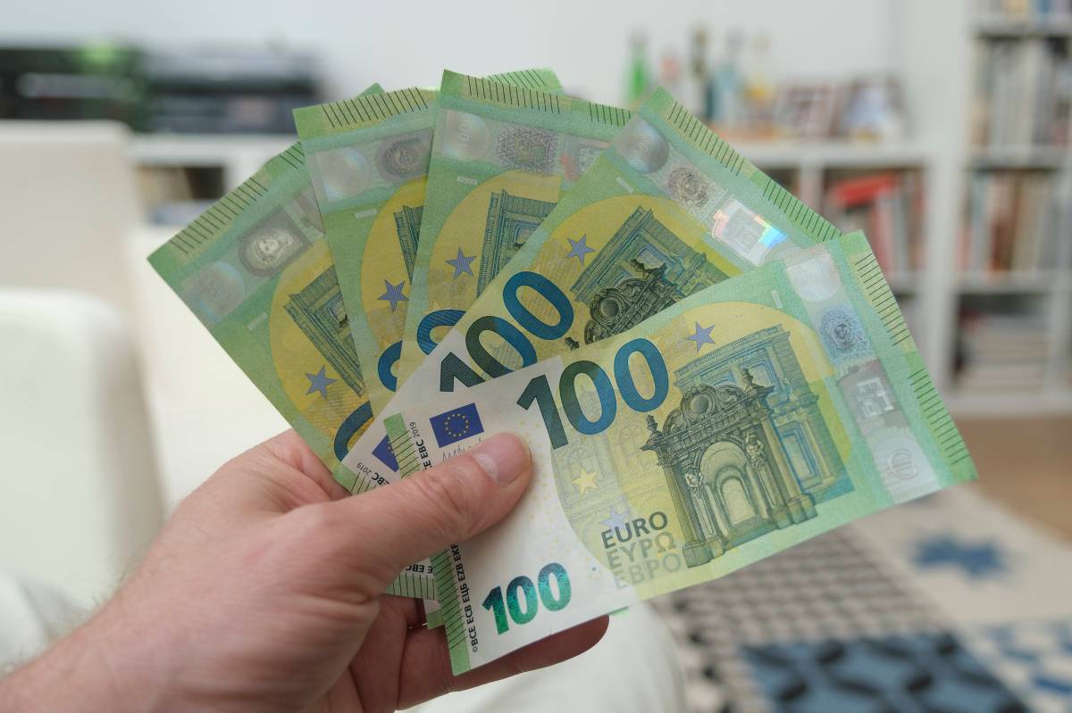 Eine Person hält fünf 100-Euro-Scheine in der Hand.