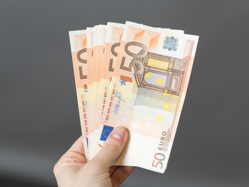 Eine Person hält mehrere 50-Euro-Scheine in der Hand.