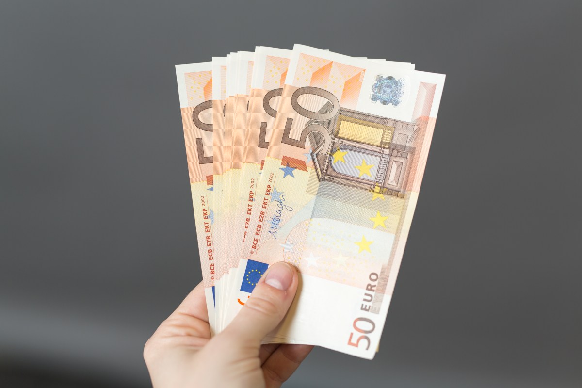 Eine Person hält mehrere 50-Euro-Scheine in der Hand.