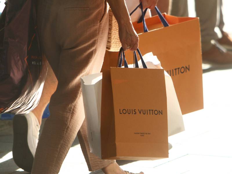 Zwei Personen tragen Tüten der Marke Louis Vuitton.