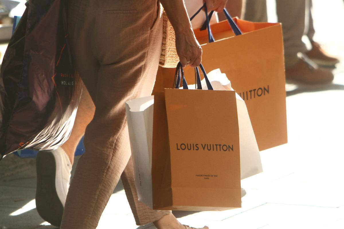 Zwei Personen tragen Tüten der Marke Louis Vuitton.