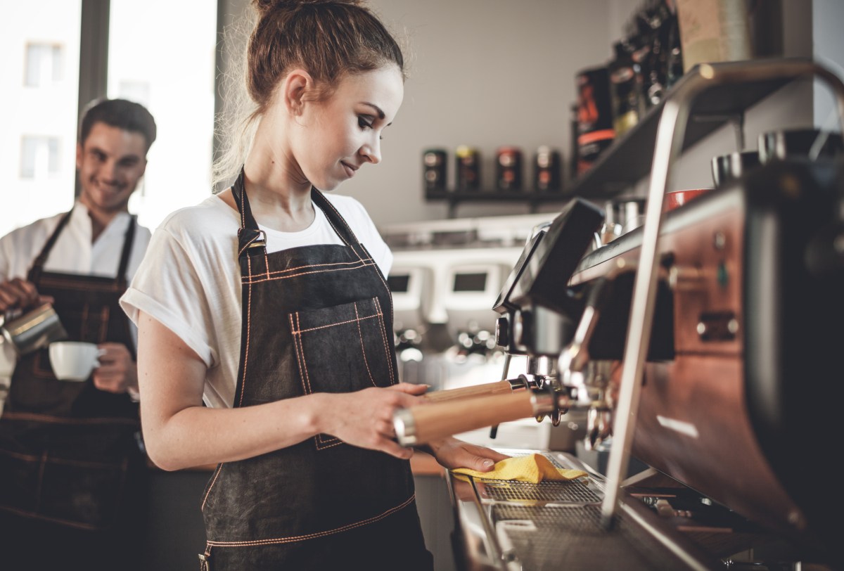 Eine Frau bereitet einen Kaffee an der Kaffeemaschine vor.