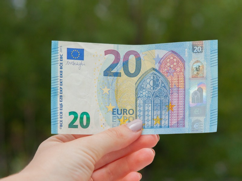 Eine Person hält einen 20-Euro-Schein in der Hand.