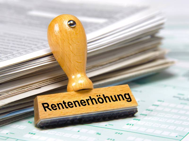 Auf einem Stempel steht das Wort "Rentenerhöhung". Darunter liegen Dokumente.