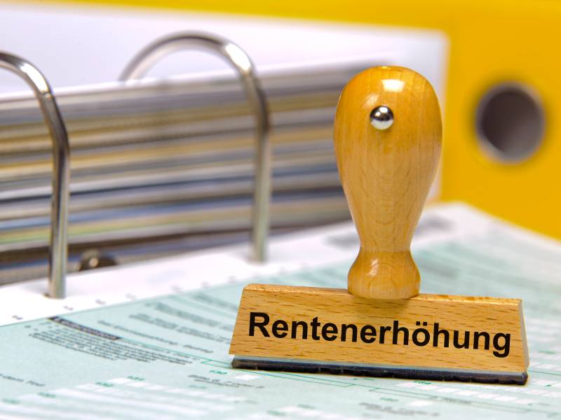 Auf einem Stempel steht das Wort "Rentenerhöhung". Darunter liegen Dokumente.