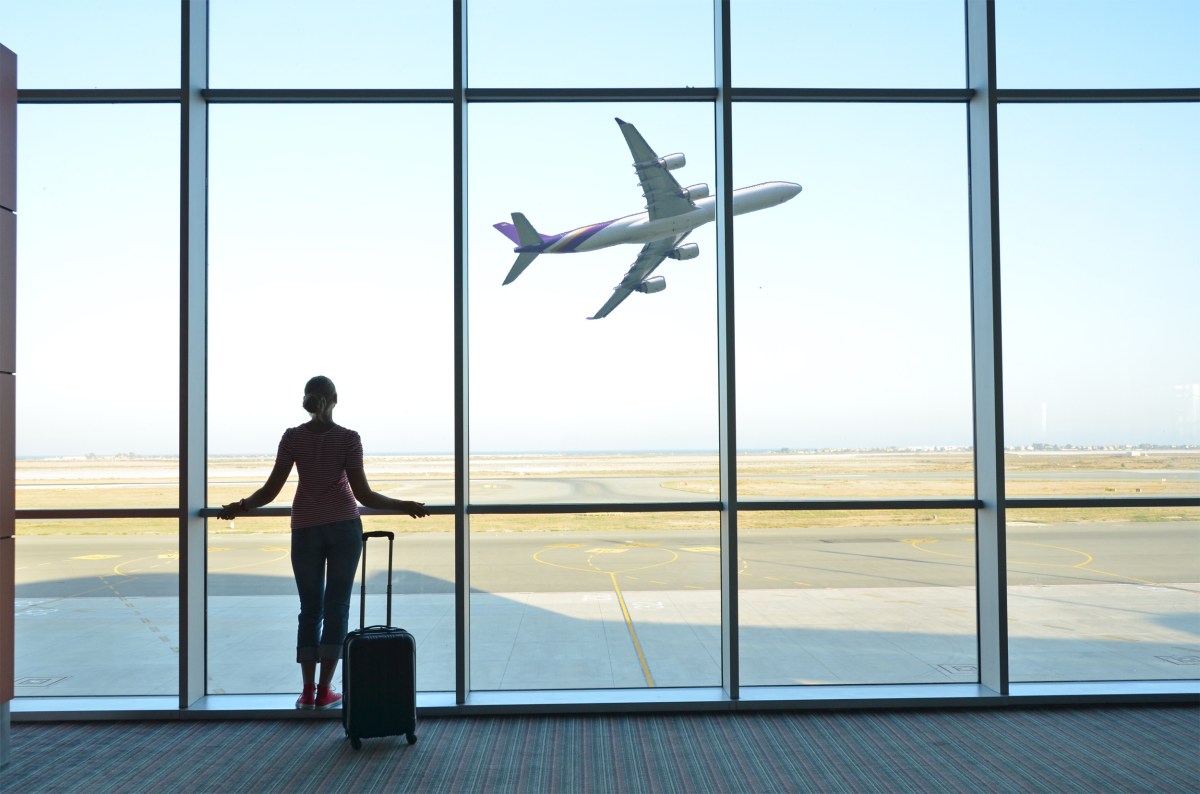 Frau steht mit Koffer am Flughafen