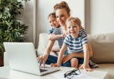 Eine Frau mit zwei kleinen Kindern sitzt vor dem Laptop.