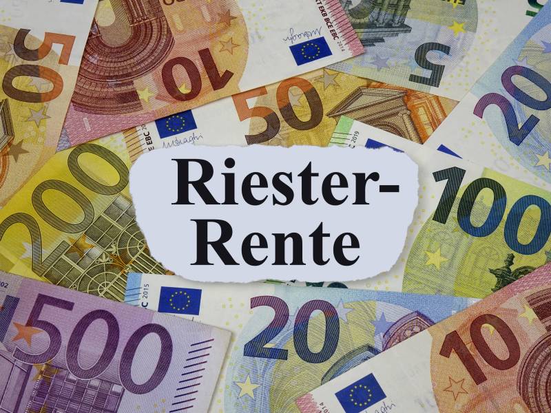 Auf einem weißen Zettel steht das Wort "Riester-Rente". Darunter liegen Geldscheine.