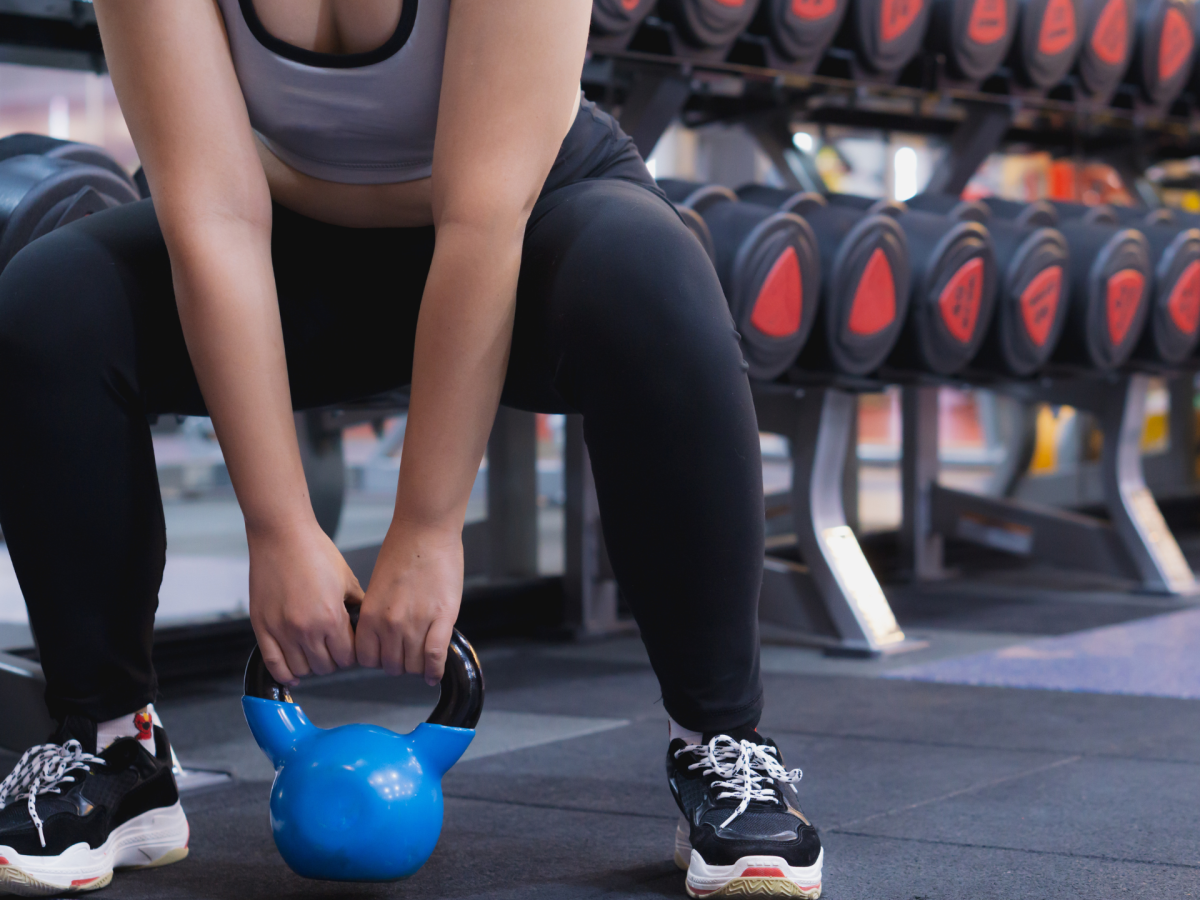 Frau im Fitnessstudio Kniebeuge mit Kettlebell