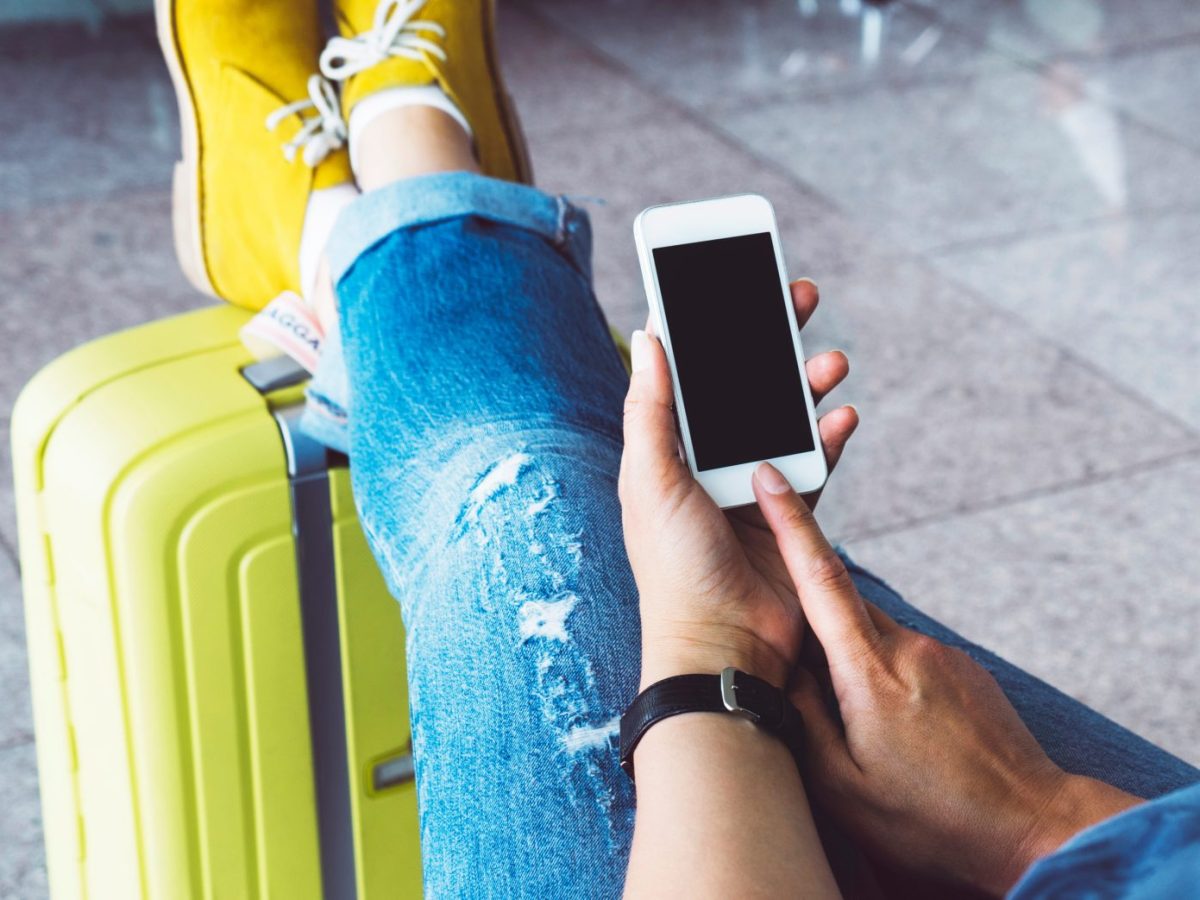 Frau mit Handy und HandgepÃ¤ck am Flughafen