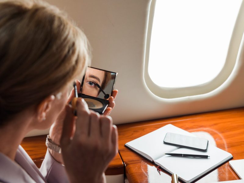 Frau schminkt sich im Flugzeug