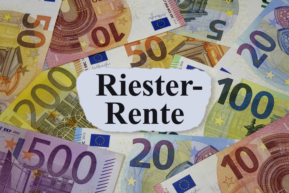 Auf einem weißen Blatt steht das Wort "Riester-Rente". Darunter liegen Geldscheine.