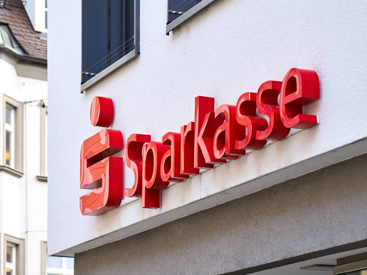 An einem GebÃ¤ude hÃ¤ngt das Logo und der Schriftzug der Sparkasse.