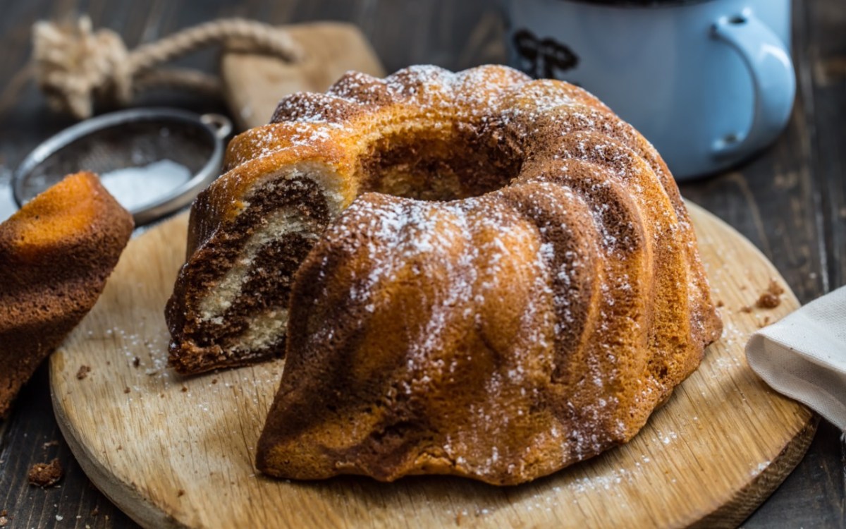 5-Minuten-Kuchen auf einem runden Holzbrett. Ein Stück wurde bereits aus dem Kuchen geschnitten.