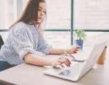 Eine junge Frau tippt auf ihrem Laptop.