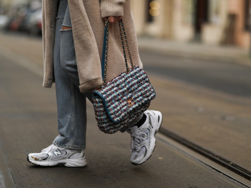 Frau geht in New Balance Sneakern über Straße.