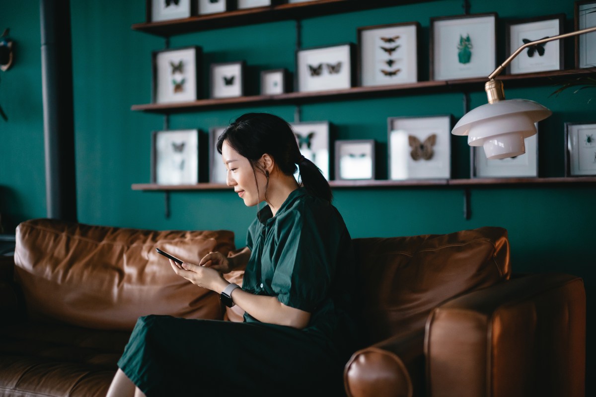 Eine Frau sitzt auf dem Sofa und schaut in ihr Online-Banking.