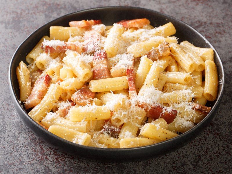 Ein Teller mit Pasta alla gricia auf dunklem Untergrund.