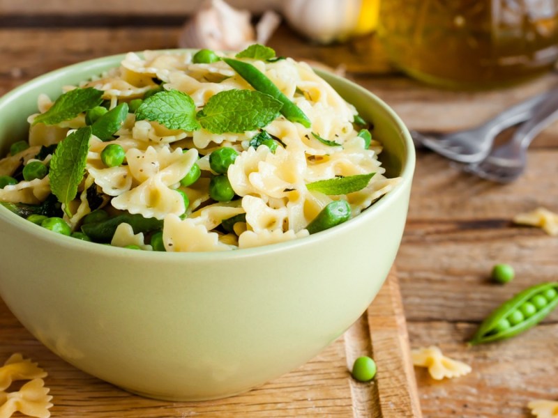 Pfefferminz-Farfalle in grüner Schüssel auf Holztisch.