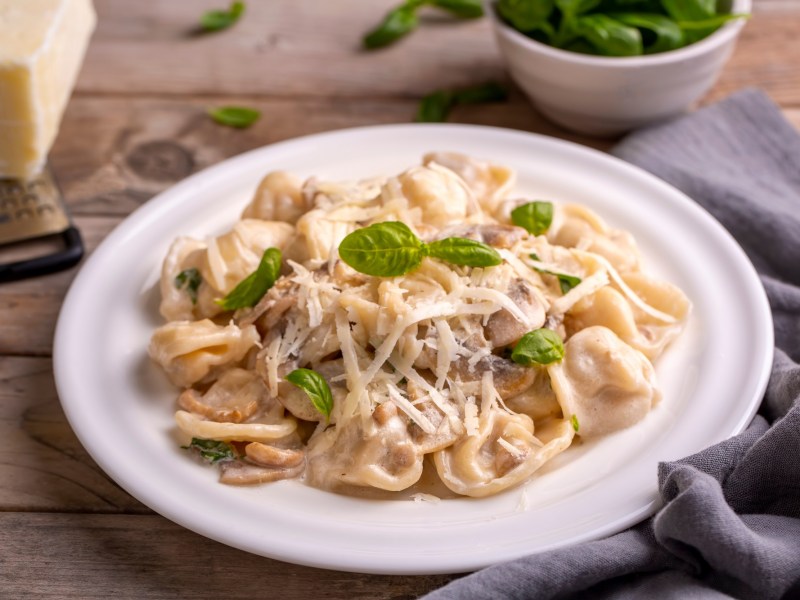 Tortellini in PilzsoÃŸe auf einem Teller.