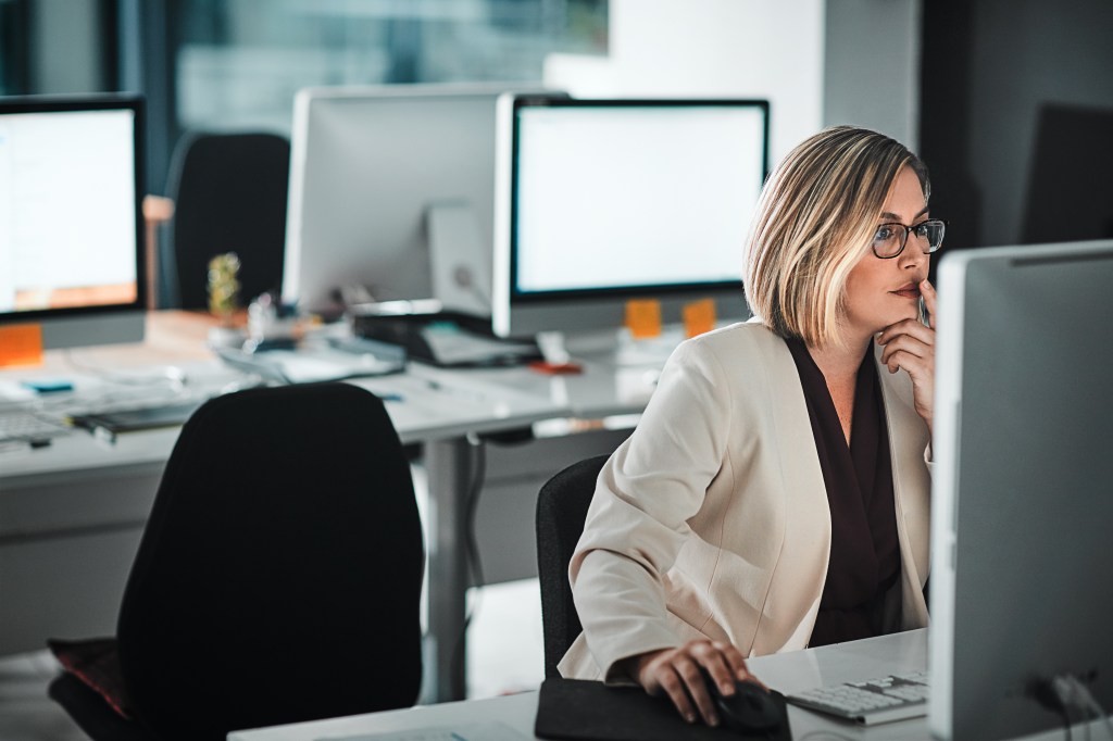 Frau sitzt noch spät abends am Computer und arbeitet.