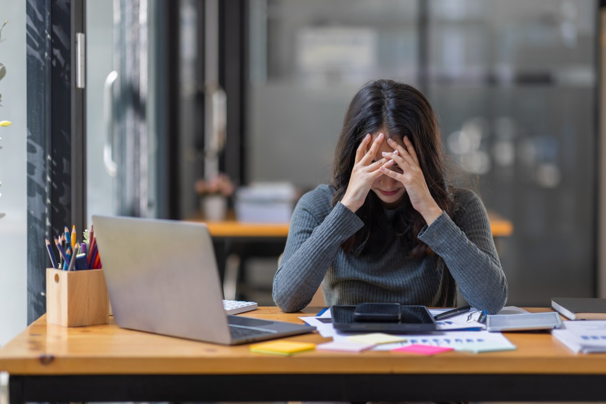 Eine Frau schlägt ihre Hände vor den Kopf. Sie sitzt im Büro.