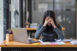 Eine Frau schlägt ihre Hände vor den Kopf. Sie sitzt im Büro.