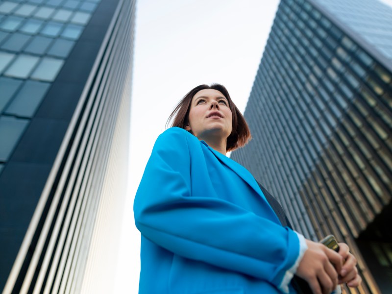 Geschäftsfrau im blauen Blazer steht in der Nähe eines Bürogebäudes