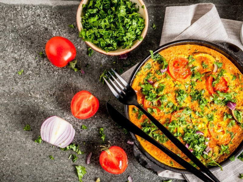 Masala-Omelett mit Pilzen auf schwarzem Teller.