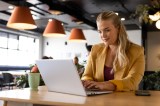 Eine Frau mit blonden Haaren sitzt im Büro und arbeitet am Laptop.