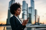 Eine Frau im Business-Anzug schaut auf ihr Handy.