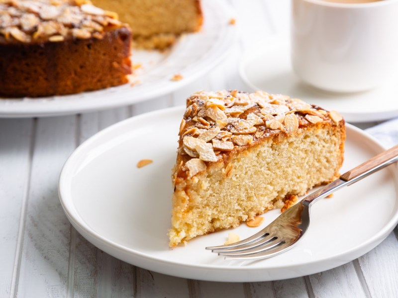 Ein StÃ¼ck Blitzkuchen mit Mandeln auf einem weiÃŸen Teller