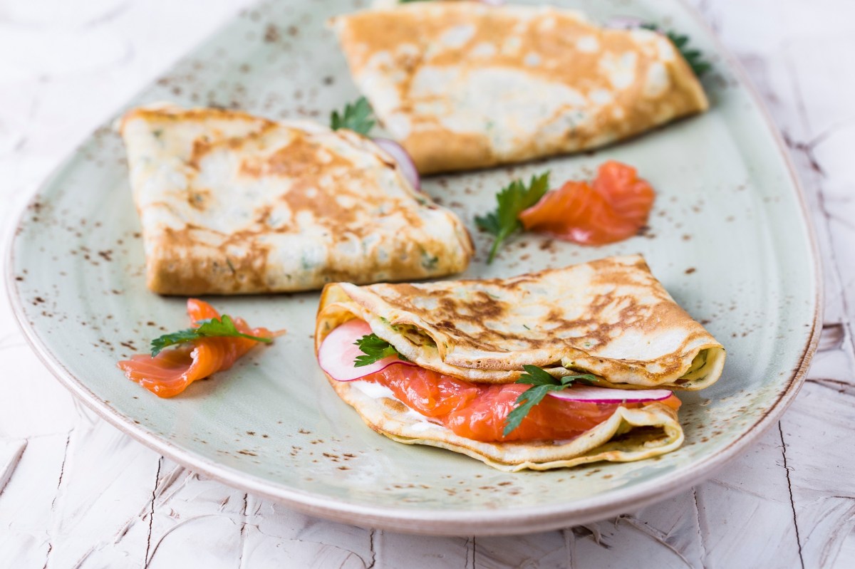 Drei Buchweizen-Pfannkuchen mit Lachs auf einem Teller.