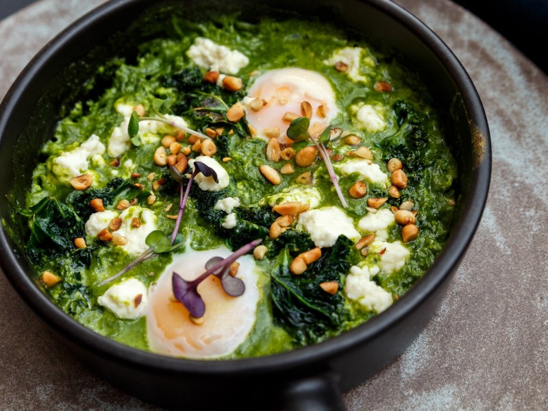 Pfanne mit grÃ¼nem Shakshuka, Pinienkernen und pochierten Eiern